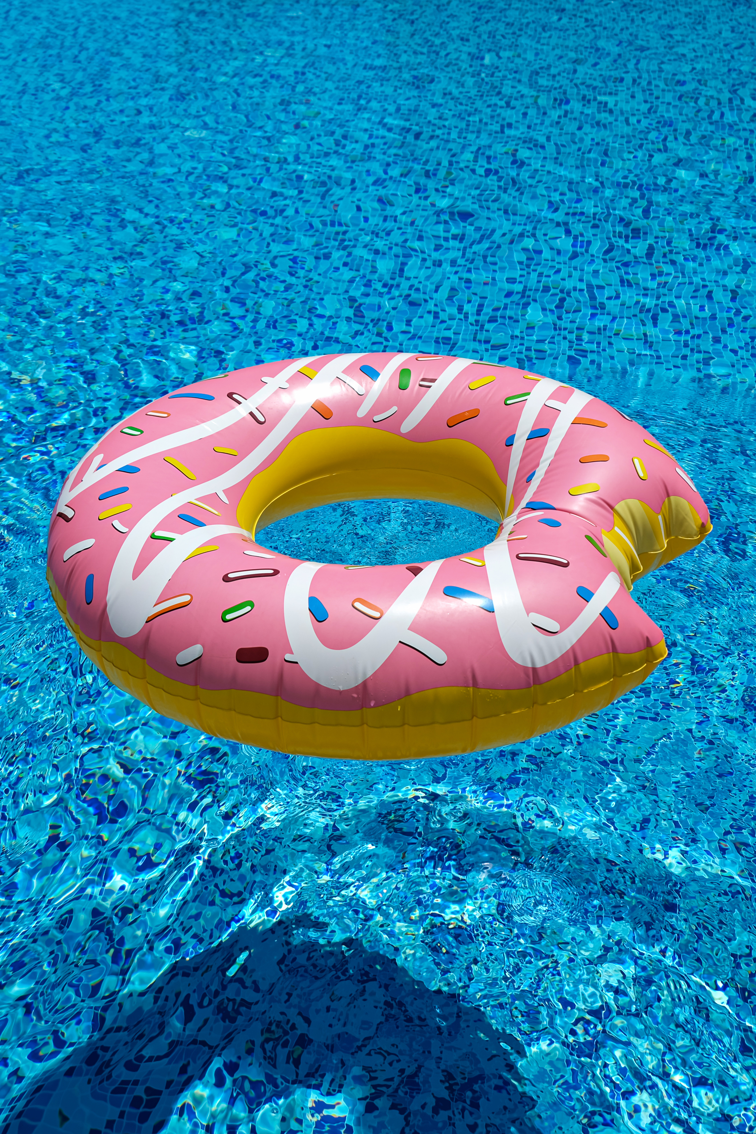 pink inflatable donut doughnut floating mattress in swimming pool. Beach pool accessories.